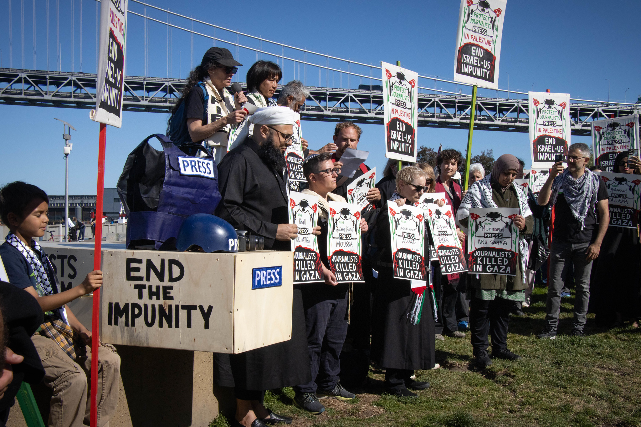 Protesters stand in a line with white signs saying "end impunity"