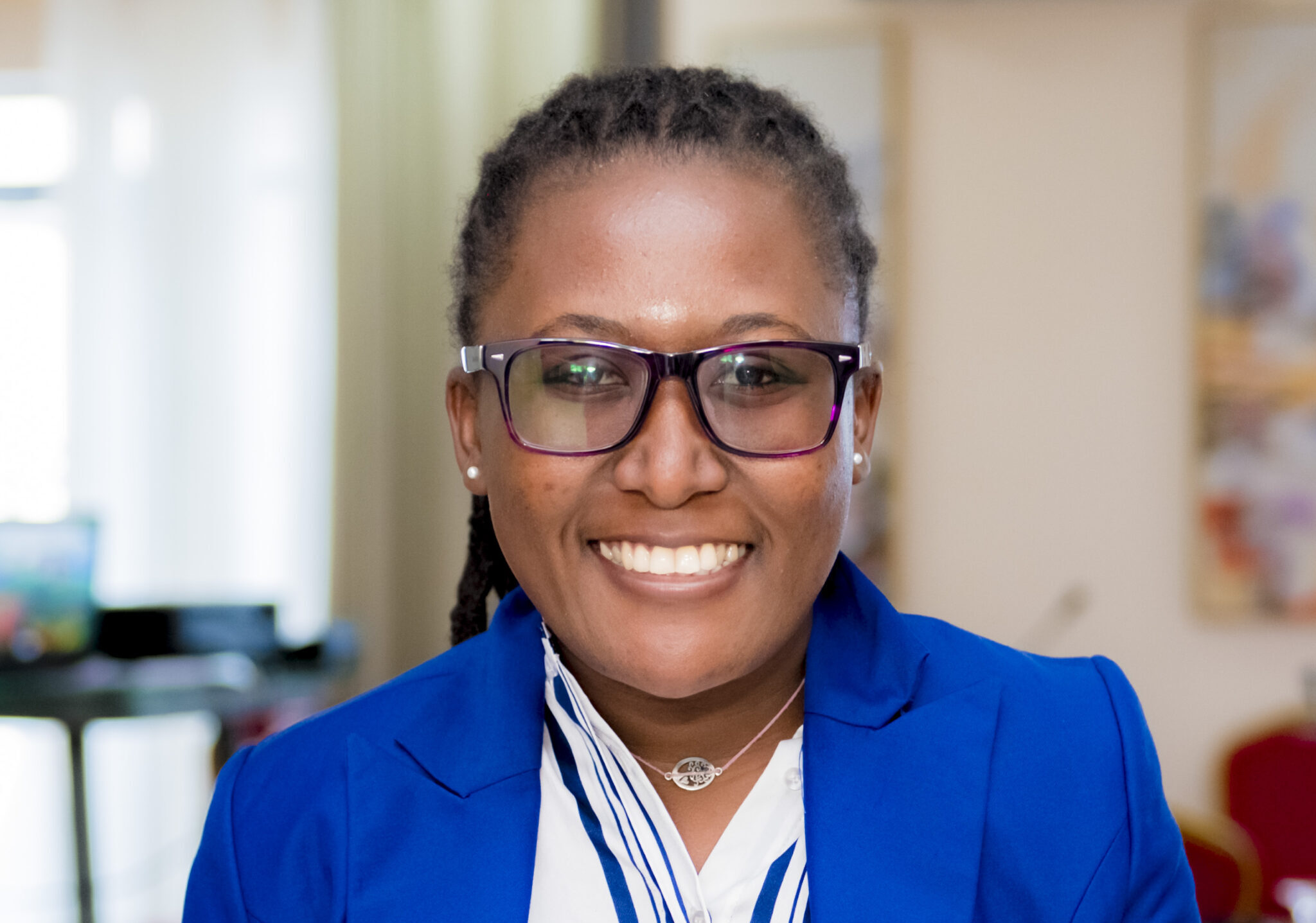 An activist smiles for the camera while wearing glasses and a blue jacket.