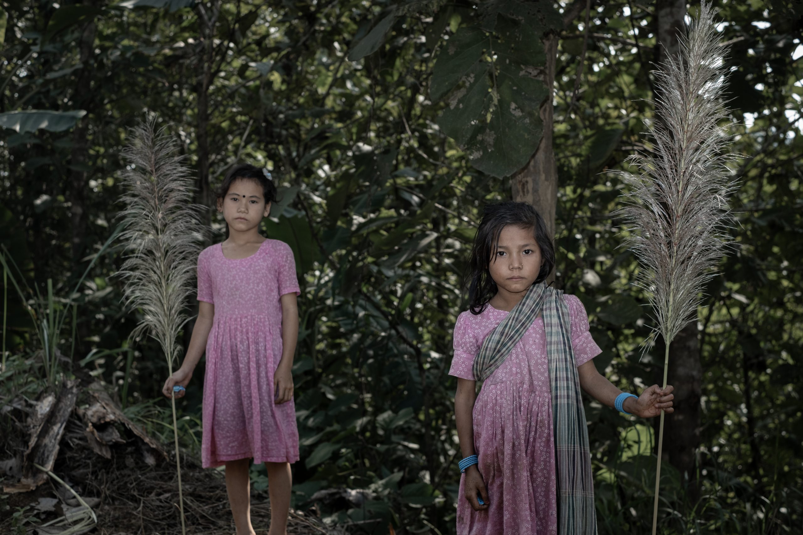 Two girls stand, waiting for the chocolates tourists throw from passing cars.